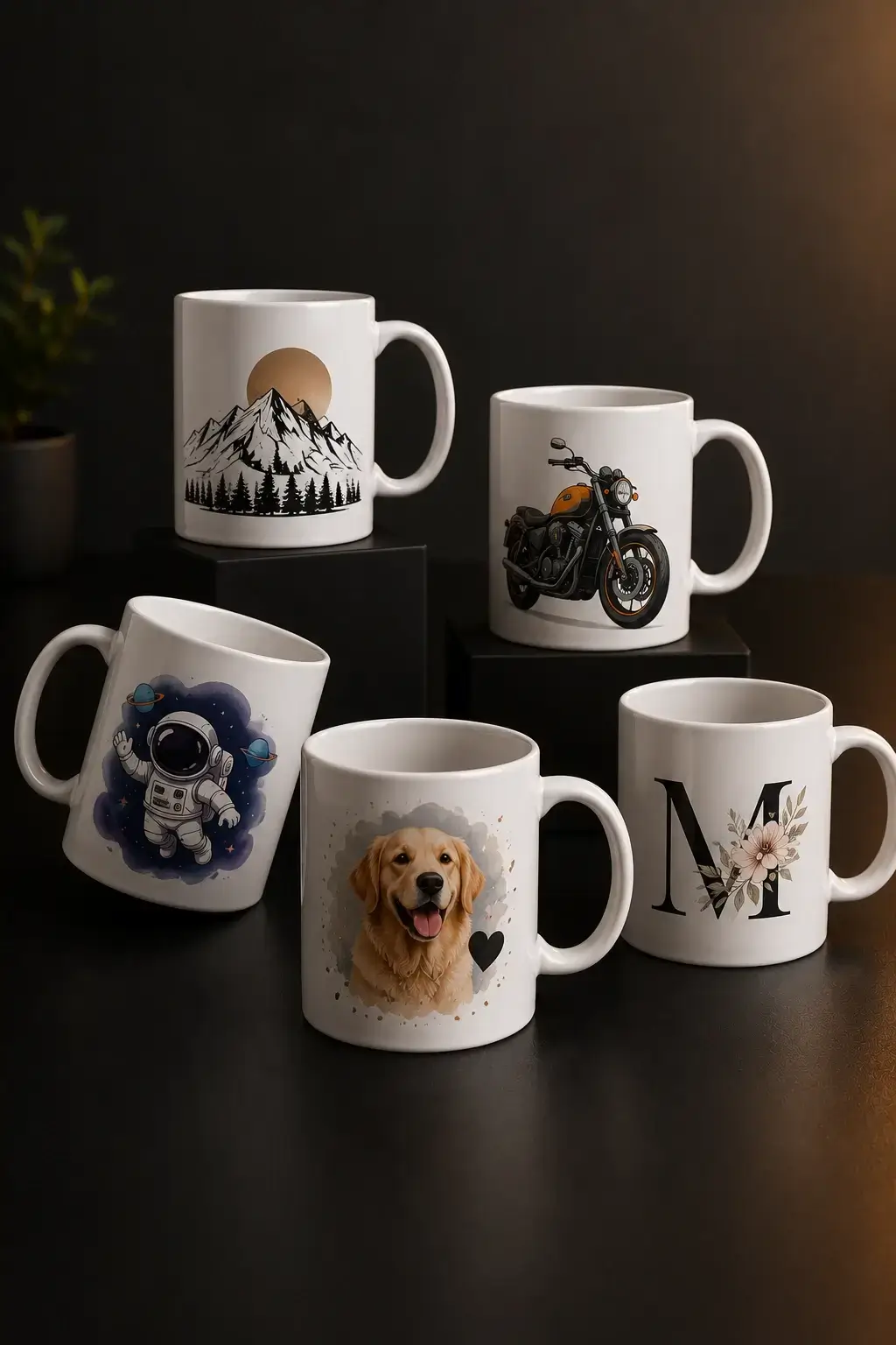 Cinco tazas blancas agrupadas sobre fondo oscuro, cada una con un diseño distinto: montañas con sol, una motocicleta, un astronauta entre planetas, un perro golden retriever y una letra M rodeada de flores